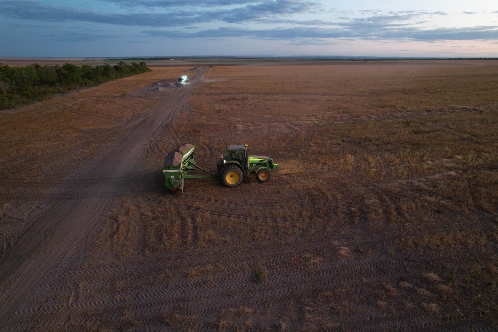 Vista aérea de trator com distribuidora aplicando remineralizador em área de plantio