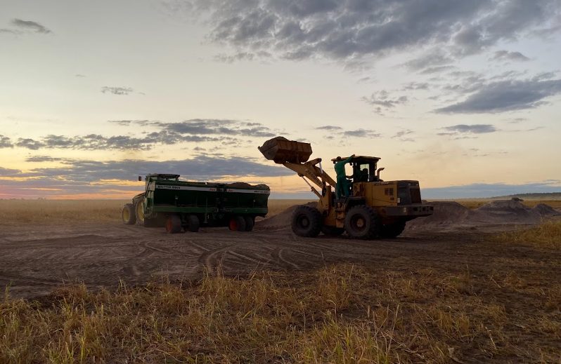 Carregamento do remineralizador na distribuidora ao entardecer, em fazenda parceira